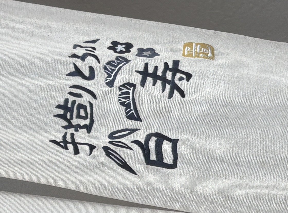 暖簾に刺繍された「手造りとうふ白寿」の版画マークと金の落款